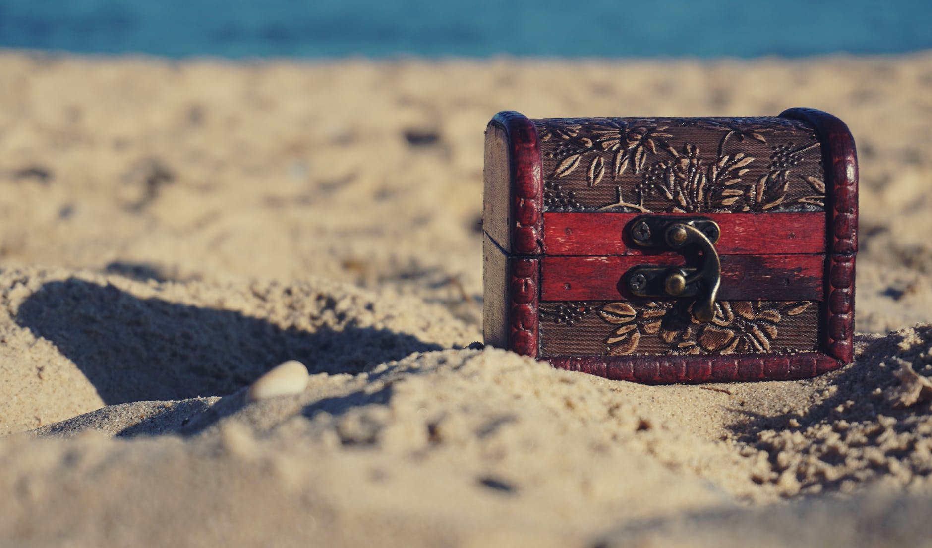 red and black wooden chest on white sand