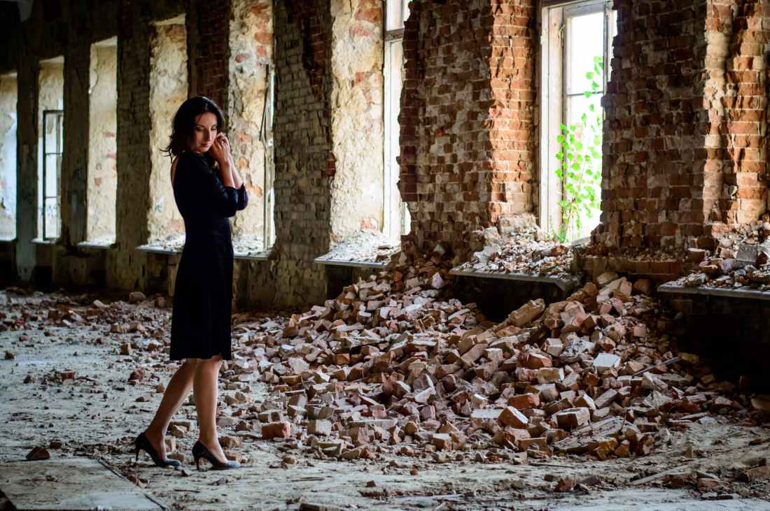 woman in black dress standing in front of pile of bricks