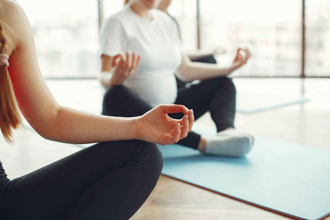 pregnant women meditating in fitness studio