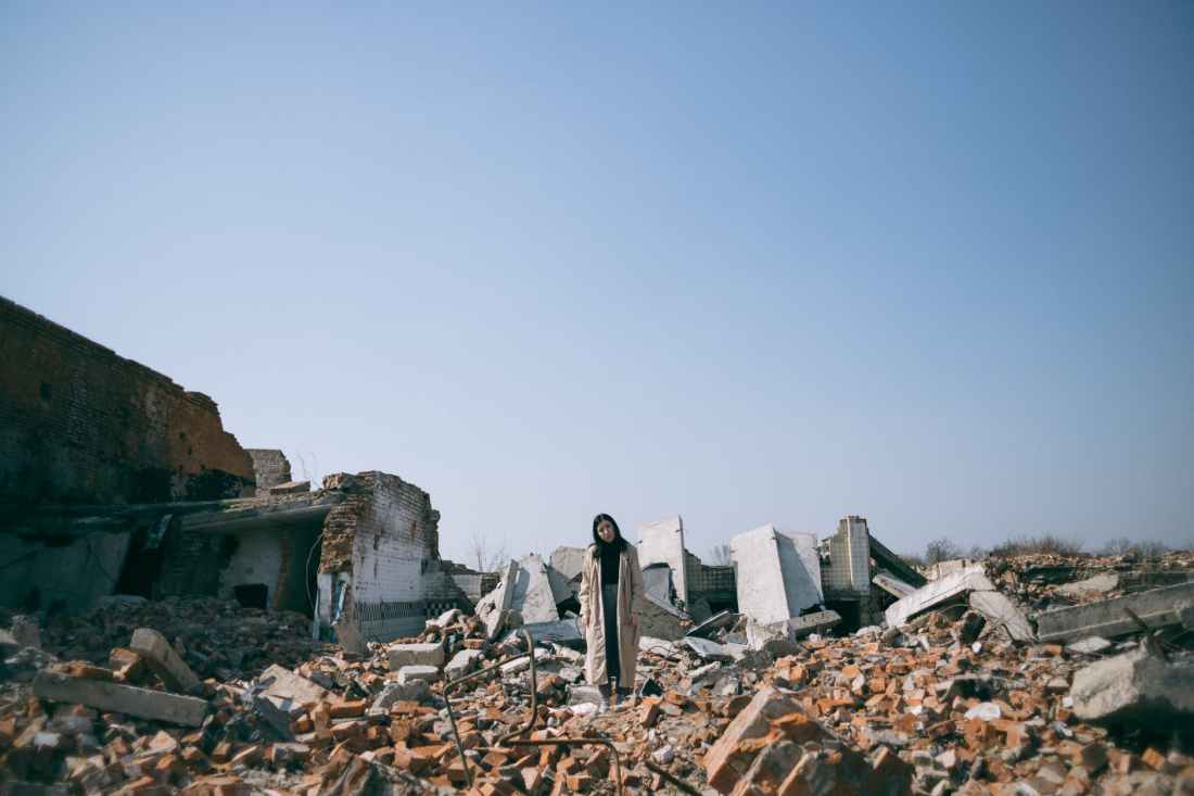 woman standing on ruins of a building