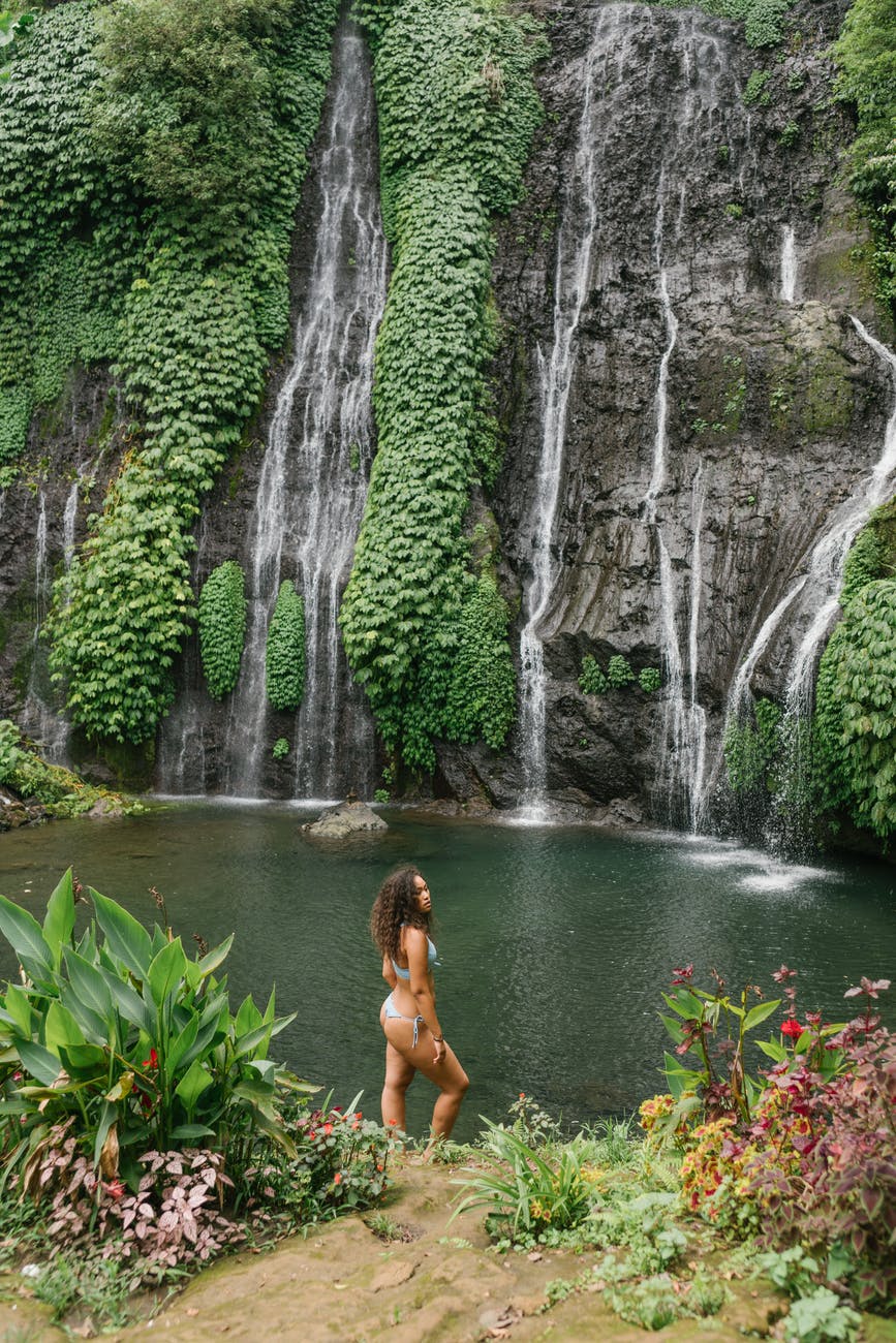 relaxed woman in swimwear enjoying day in rainforest near waterfall
